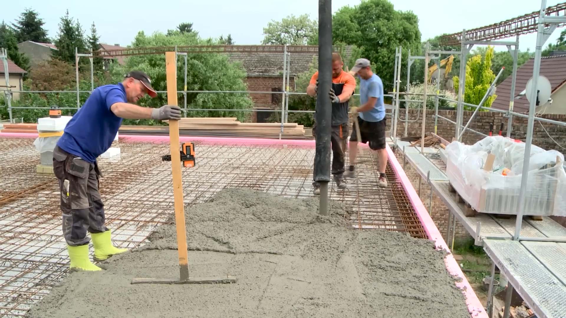 Mauerwerk Hausbau: Drei Männer stehen auf einer Decke. Die Decke besteht momentan nur aus Stahldräthen und wird auf dem Bild mit Beton aufgegossen