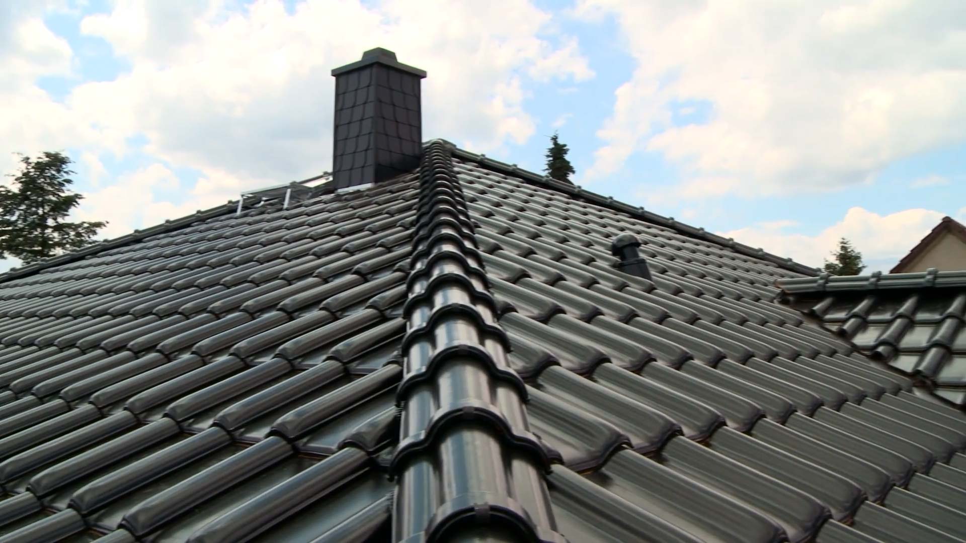 Dachstuhl bauen: Das Bild zeigt ein Dach mit dunklen Ziegeln. Das Dach ist leicht von unten nach oben geschossen.