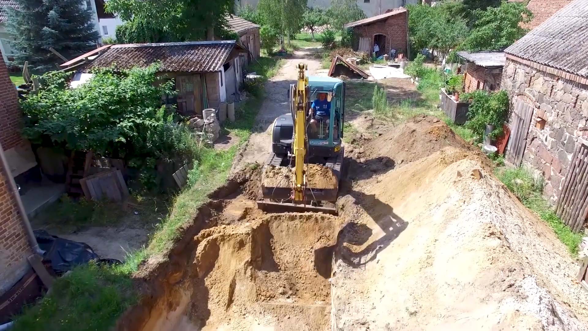 Rohinstallation Sanitär und Heizung: Ein gelber Bagger baggert Erde auf.