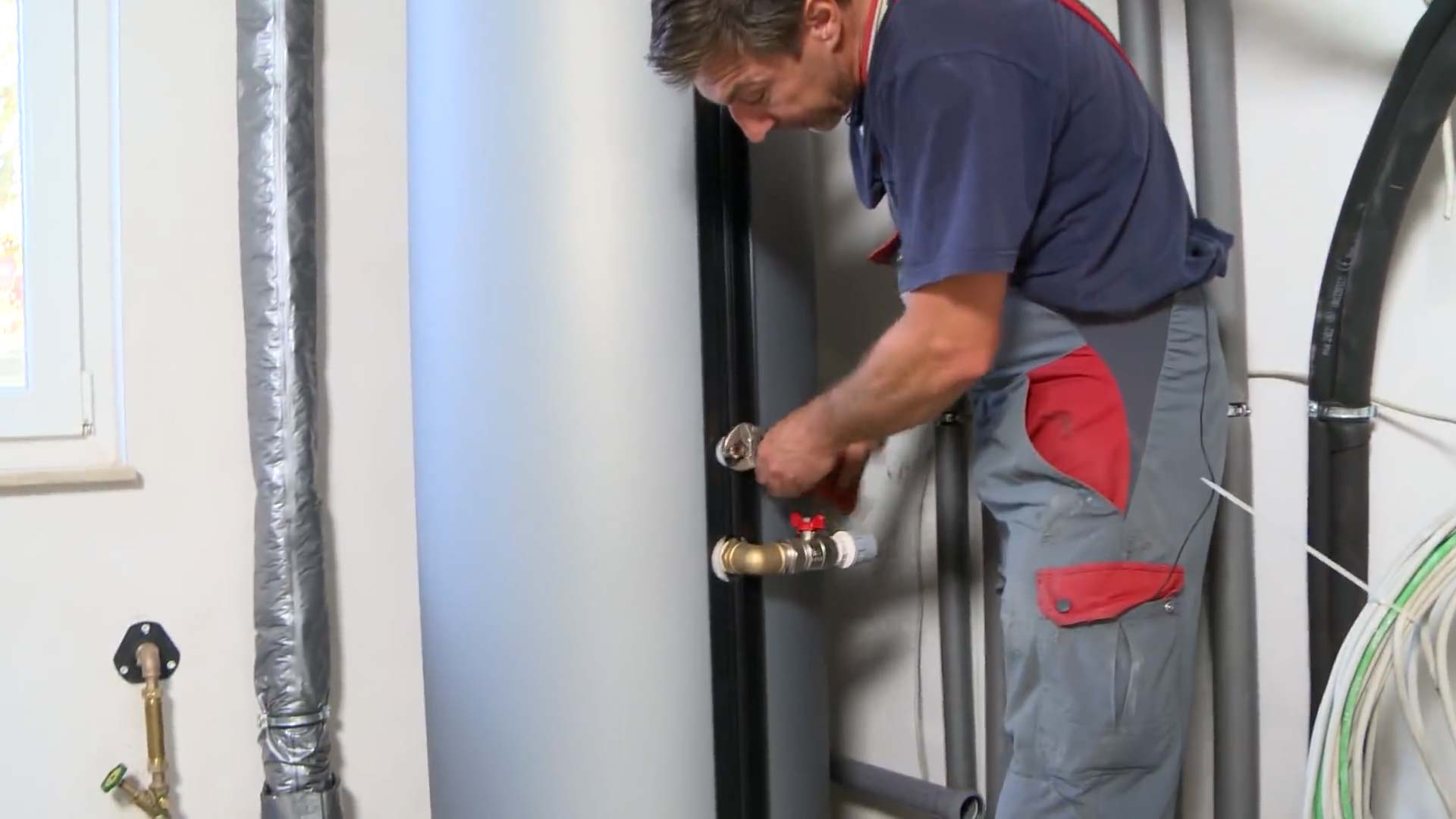 Elektroinstallation Wärmepumpe: Monteur montiert Rohrhalterungen und verlegt Verbundrohre für Vor- und Rücklauf.