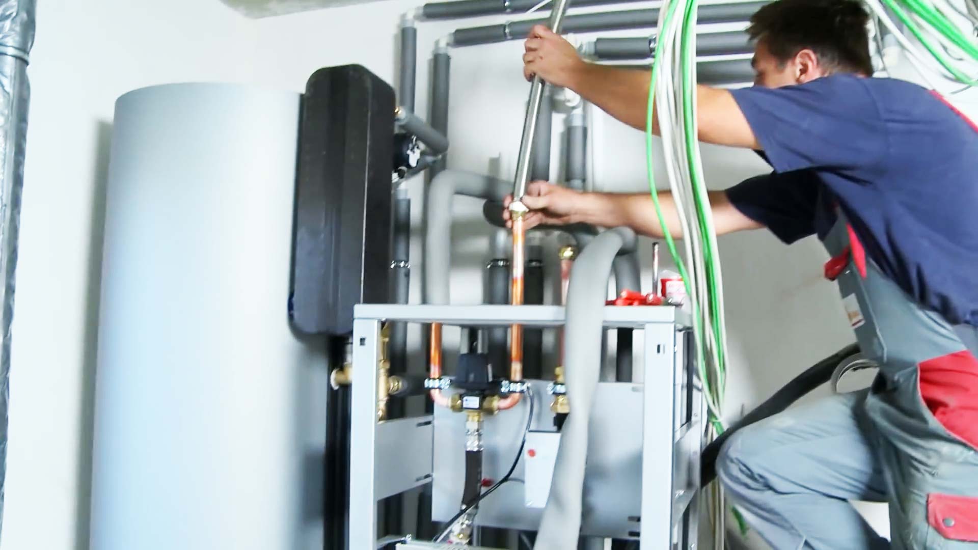 Elektroinstallation Wärmepumpe: Monteur verbindet die Wärmepumpe mit der Fußbodenheizung und dem Pufferspeicher.