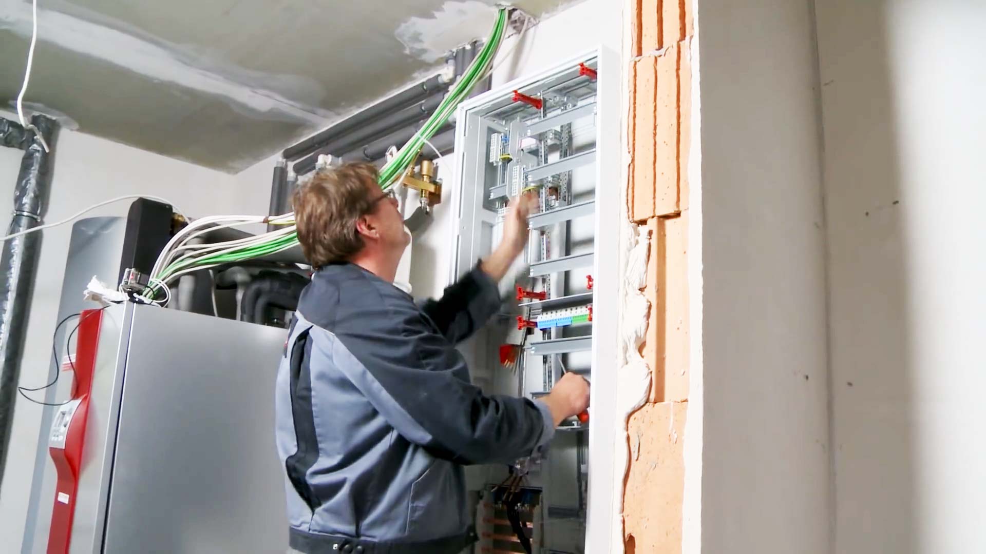 Elektroinstallation Wärmepumpe: Elektriker setzt die erste Klemmschiene für Neutral- und Schutzleiter und installiert die Schaltelemente auf den Hutschienen.